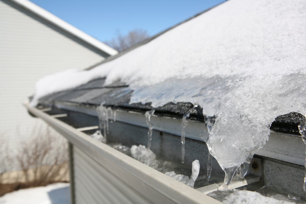 Ice and snow-covered roof in need of routine winter roof repair & maintenance 